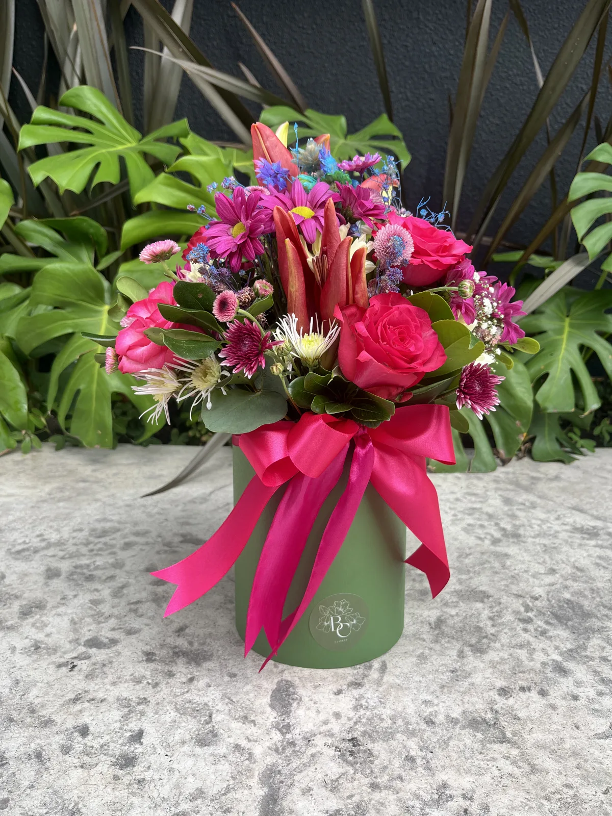 Arranjo em box verde com flores coloridas e laço rosa